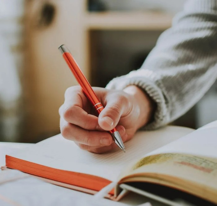 Mains en train d'écrire, l'une tenant un stylo