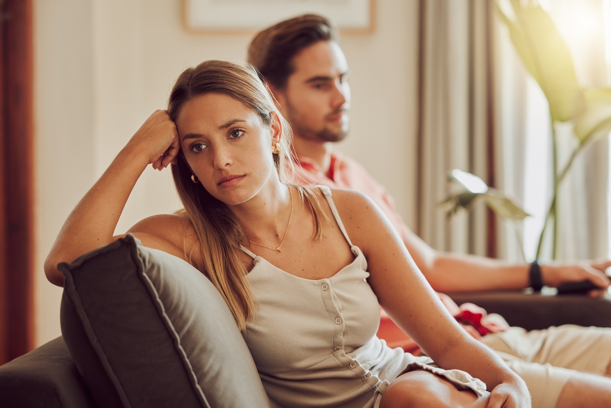 Couple assis dos à dos sur un lit, dans le silence