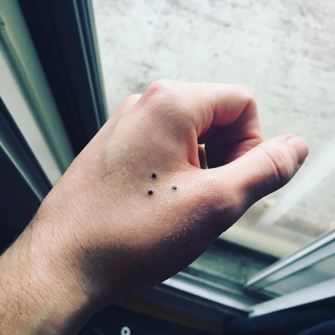 Tatouage minimaliste à trois points sur une main