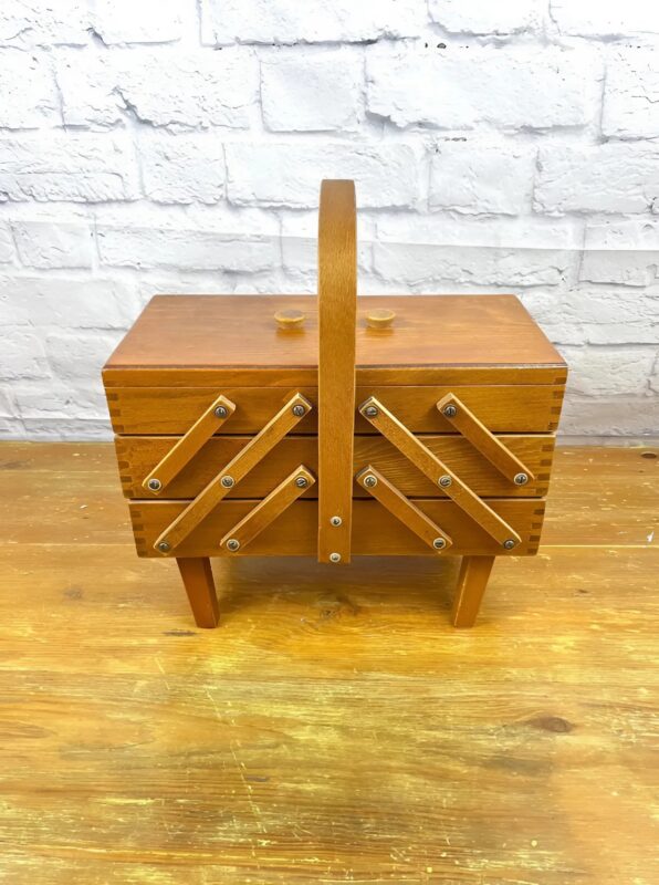 Une grand-mère souriante tenant une boîte à couture ancienne