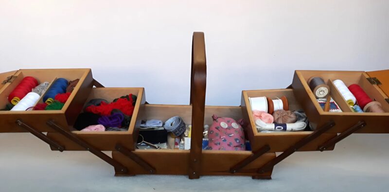 Compartiment secret ouvert d'une boîte à couture, montrant de la dentelle et des lettres