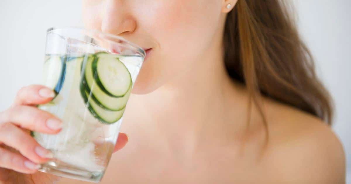 Femme buvant de l'eau de concombre