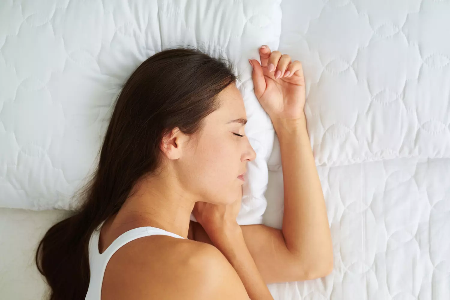 Femme dormant en position fœtale sur le côté, entourée d'oreillers