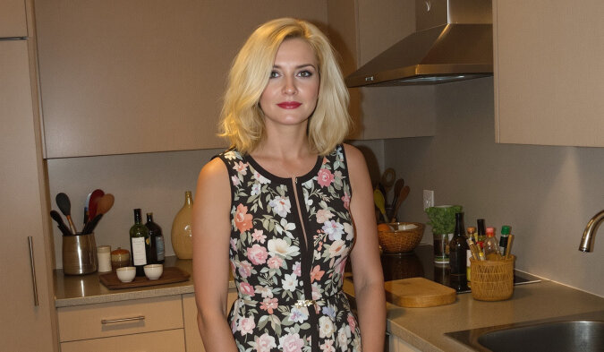 Une femme regarde par l'entrebâillement d'une porte d'entrée, illustrant une confrontation tendue.