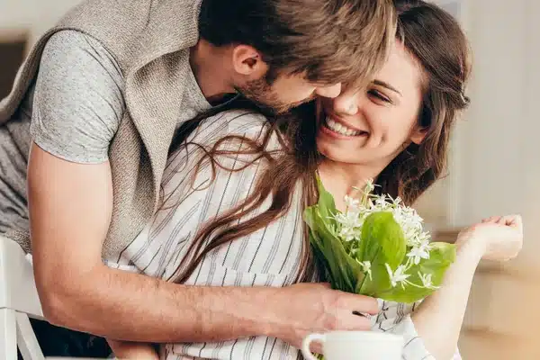 Couple s'enlaçant avec un bouquet de fleurs