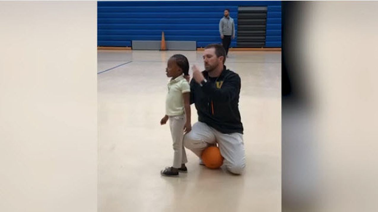 Entraîneur agenouillé attachant les cheveux d'une petite joueuse de basket
