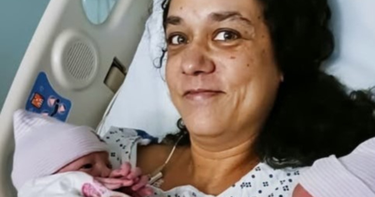 Femme d'âge mûr tenant une échographie, l'air à la fois surprise et émue.