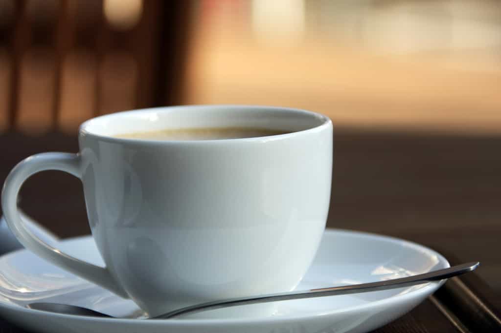 Tasse de café noir fumant sur une table en bois