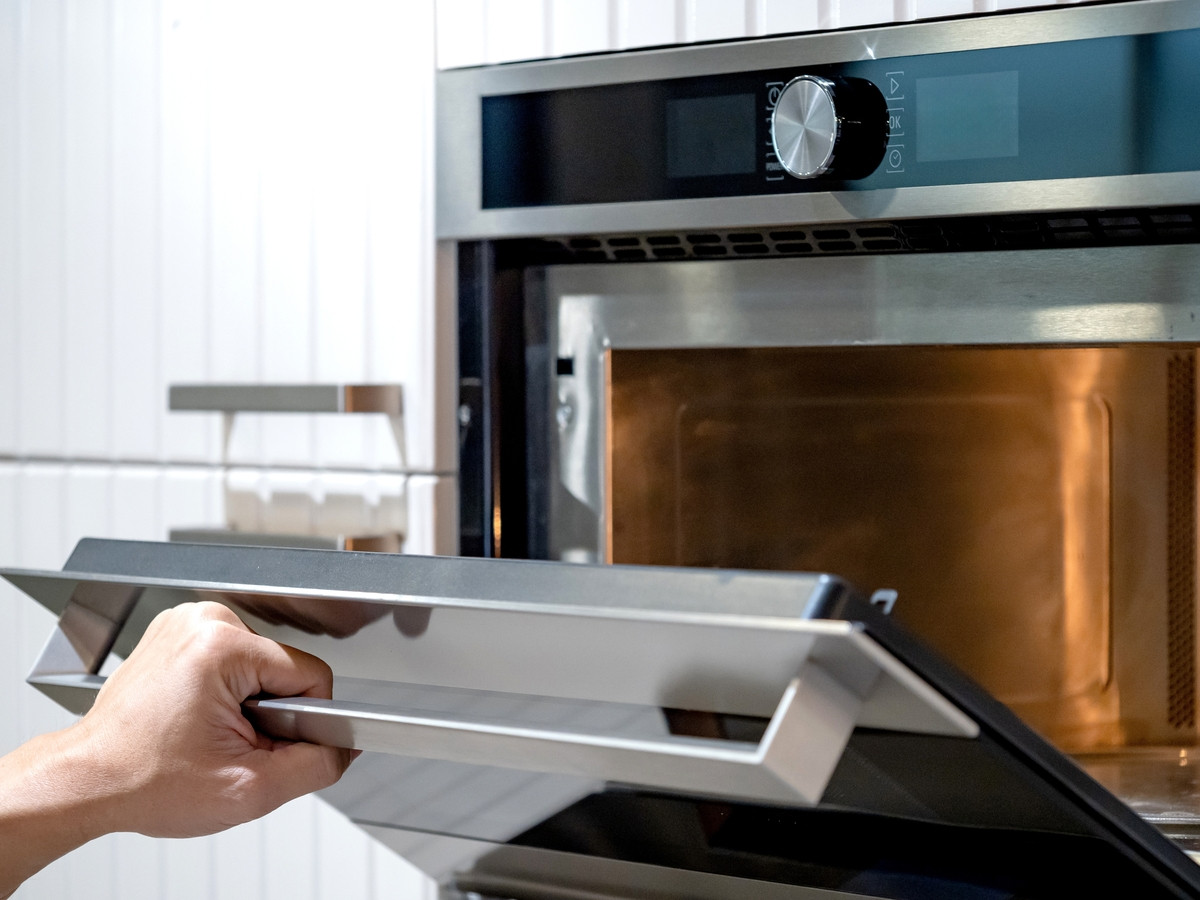 Femme nettoyant son four avec des produits adaptés